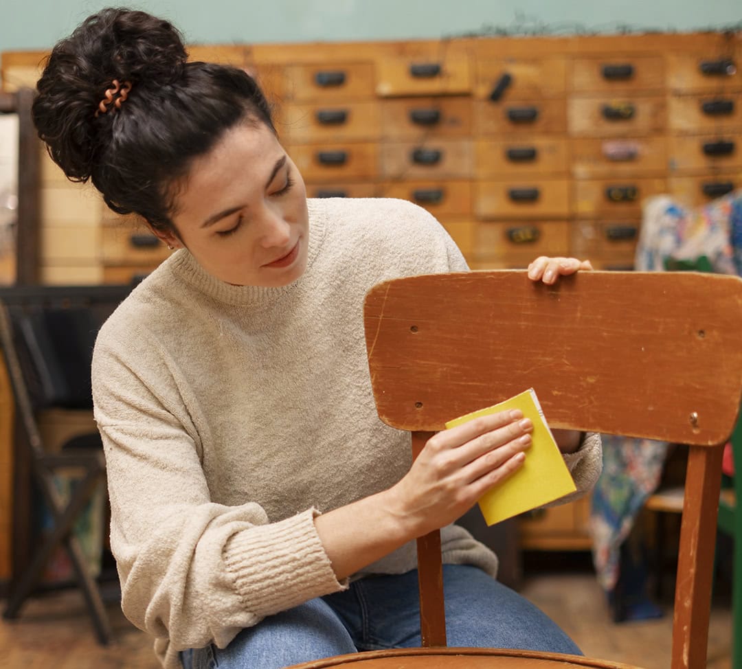 woman sanding old chair