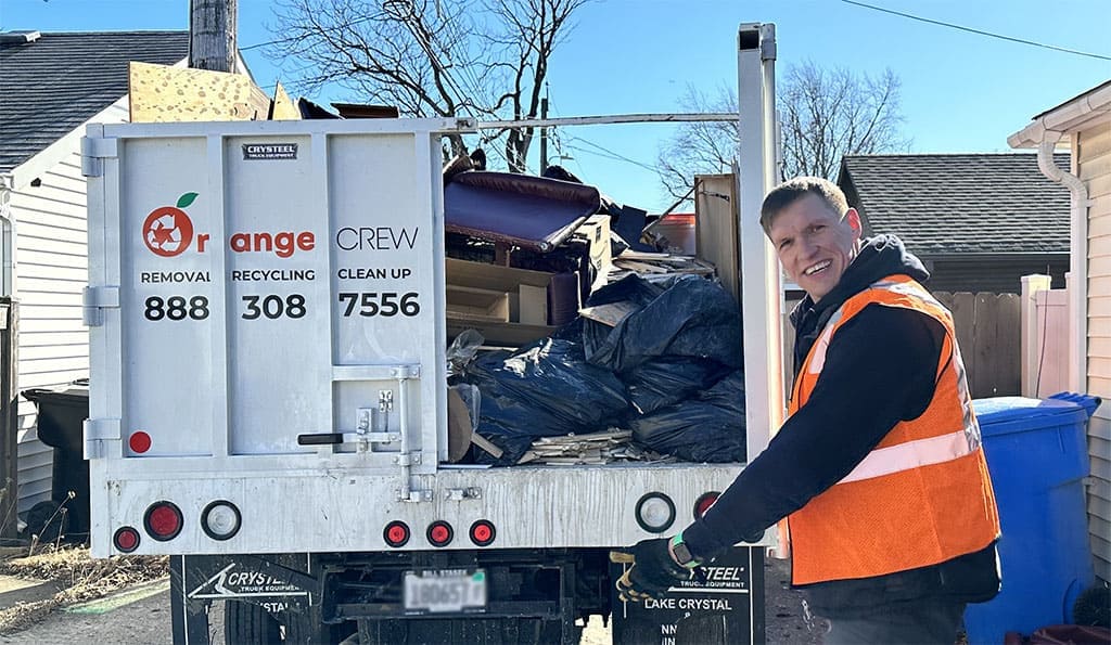 man standing next to orange crew truck with open bed door