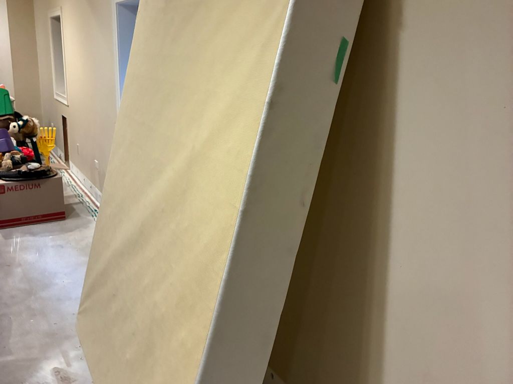 Queen box spring leaning against a basement wall ready for removal in Clarendon Hills
