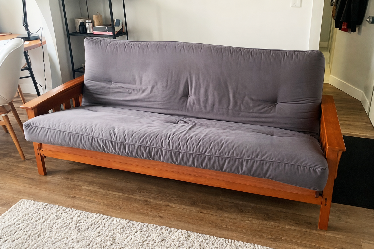 Wooden frame futon couch with mattress in a studio apartment