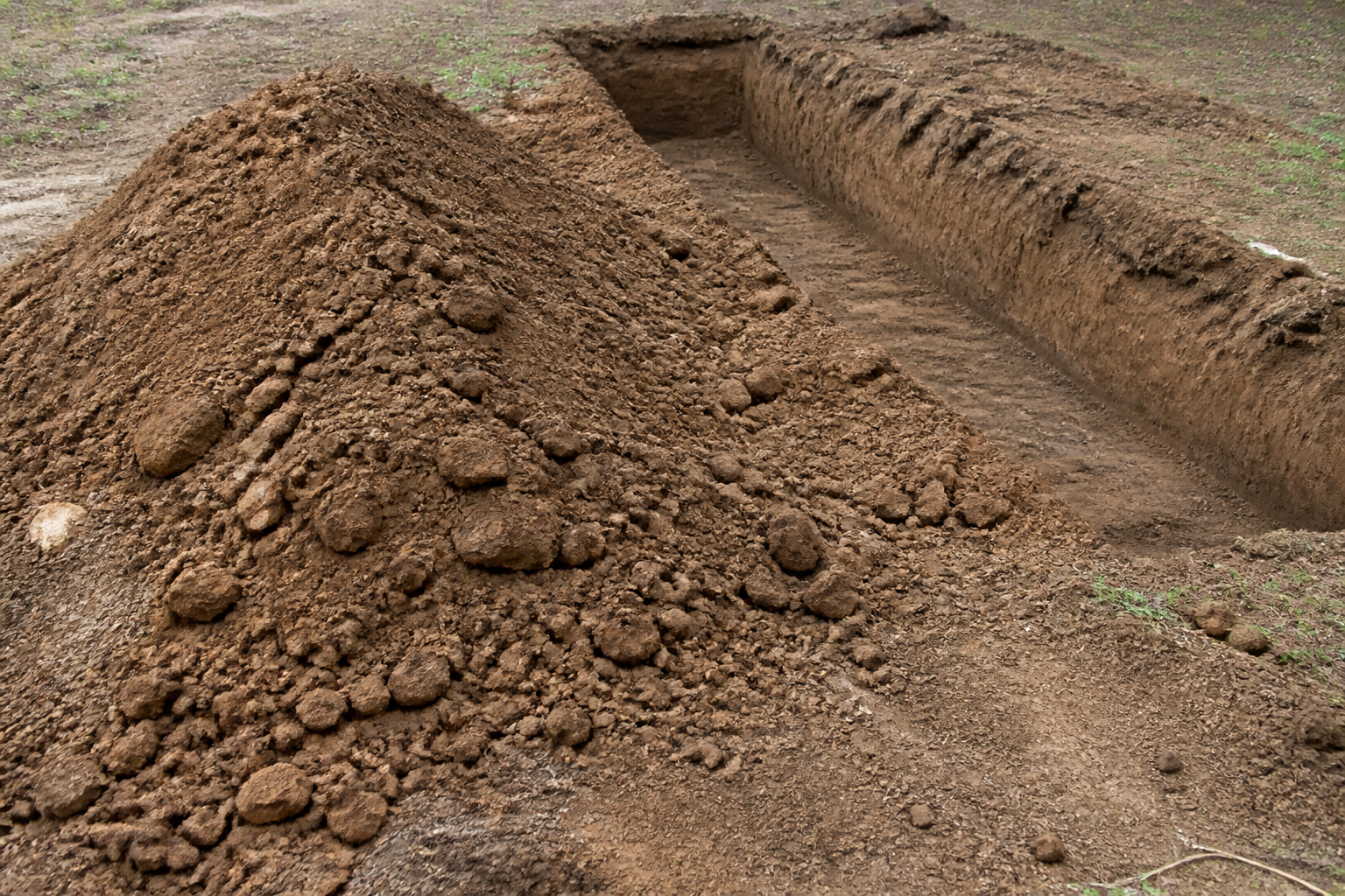 Mound of excavated dirt beside a dug trench